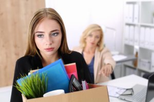 Boss dismissing an employee. Dejected fired office worker carrying a box full of belongings.